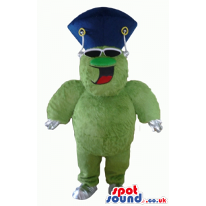 Smiling green and white monster wearing a blue top hat and dark