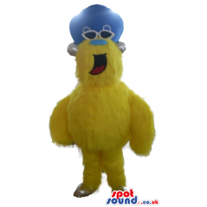 Yellow furry monster with a light blue nose wearing dark