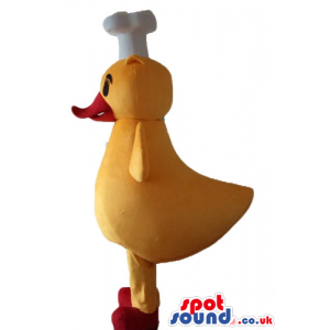 Yellow chicken with a red beak and feet wearing a chef's hat -