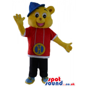 Yellow bear wearing a red and white shirt, black trousers, blue