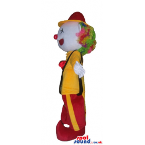 Clown with multicolored hair and a red nowse wearing a yellow