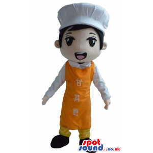 Boy wearing a chef's hat, an orange apron with writings in