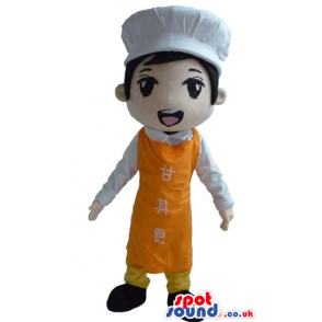 Boy wearing a chef's hat, an orange apron with writings in