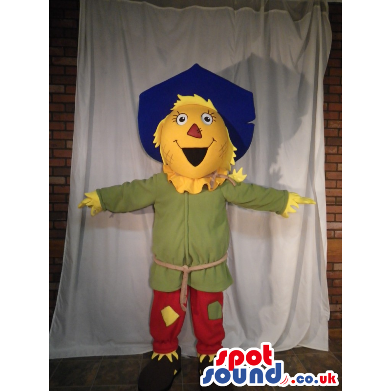 Scarecrow Character Mascot Wearing A Blue Hat And Red Pants -