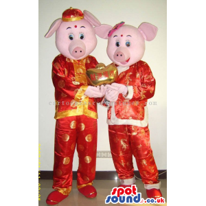 Pig Couple Mascots Wearing Red And Golden Oriental Clothes -