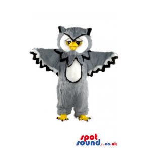 Furry owl mascot with a his wings wide spread and standing -