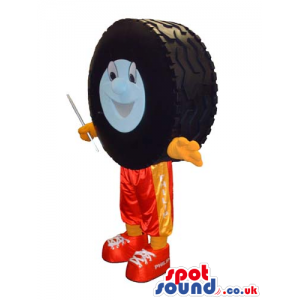 Big Car Wheel Tyre Mascot With A Face Wearing Orange Pants -