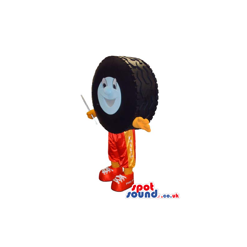 Big Car Wheel Tyre Mascot With A Face Wearing Orange Pants -