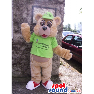 Brown Bear Mascot Wearing A Green Cap And A T-Shirt With Text -