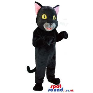 Cute black cat mascot with yellow eyes standing with small tail