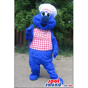 Blue Monster Mascot Wearing A Checked Apron And A Chef Hat -