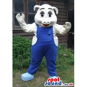 White piglet wearing a blue jumper and shoes looking very happy