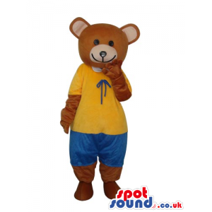 Brown Teddy Bear Mascot Wearing A Yellow Shirt And Blue Pants -