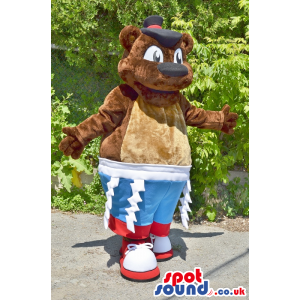 Brown Bear Plush Mascot Wearing Blue And Red Shorts And A Hat -