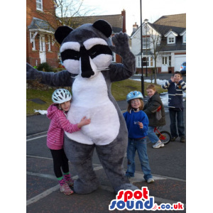 Grey badger mascot with white underbelly and black and white face