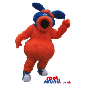 Red And Blue Hairy Mascot With A Big Round Mouth And Ears -