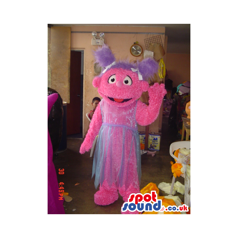 Tall pink friendly looking monster mascot with violet pig tails