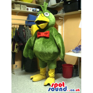 Green Parrot Plush Mascot Wearing A Red Bow Tie And Glasses -