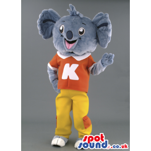 Tall overjoyed Koala mascot wearing orange T-shirt with K