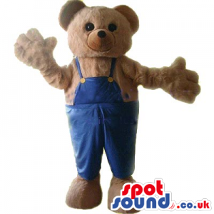 Cute Brown Teddy Bear Plush Mascot Wearing Blue Overalls. -