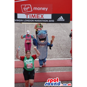 Blue and grey shark mascot holding a bloodied human leg -