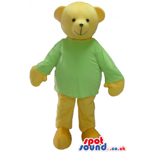 Smiling beige bear wearing a green sweater and beige trousers -