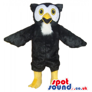 Black owl with black and white face, yellow eyes, yellow legs