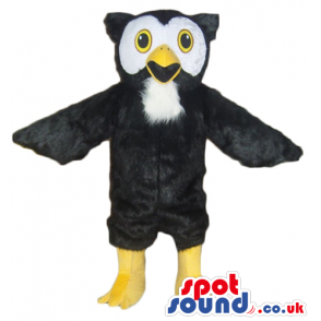 Black owl with black and white face, yellow eyes, yellow legs