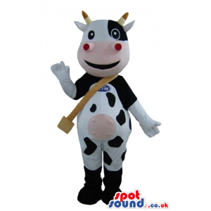 Smiling black and white cow with yellow horns, a pink mouth and