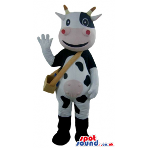 Smiling black and white cow with yellow horns, a pink mouth and