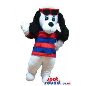 White dog with furry black ears wearing dark glasses with a red